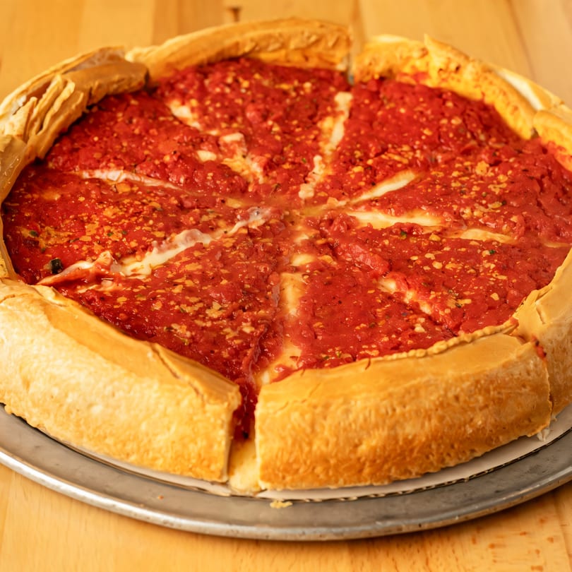 A deep-dish Sicilia's Pizzeria pizza with thick crust, rich red sauce, and melted cheese.